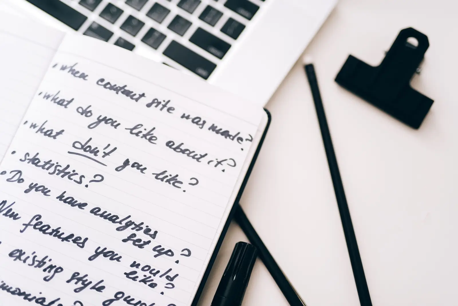 Laptop-এর পাশে handwritten notebook রেখে digital note-taking app selection plan করা হচ্ছে