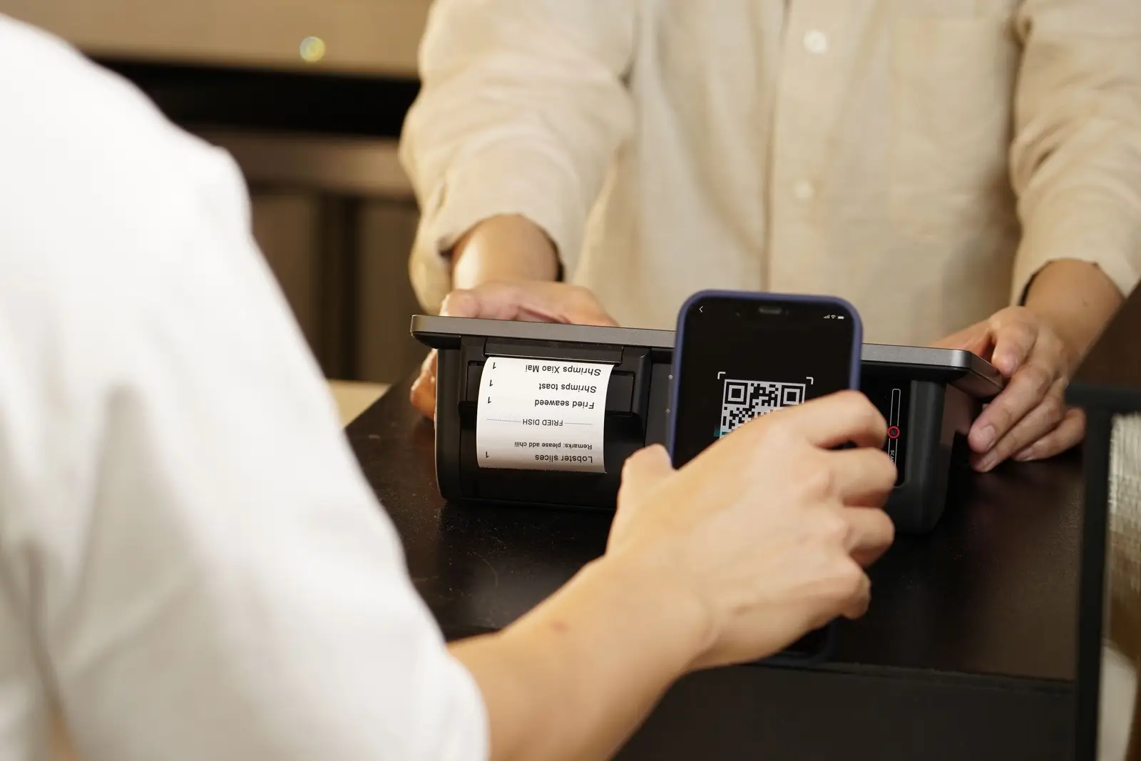Retail counter-এ smartphone দিয়ে QR code scan করার আগে payment details যাচাই করছেন একজন customer